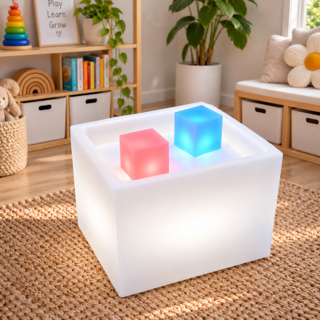Sensory Mood Play Cube glowing white in a playroom, with the two smaller colour changing cubes sitting in the well on top