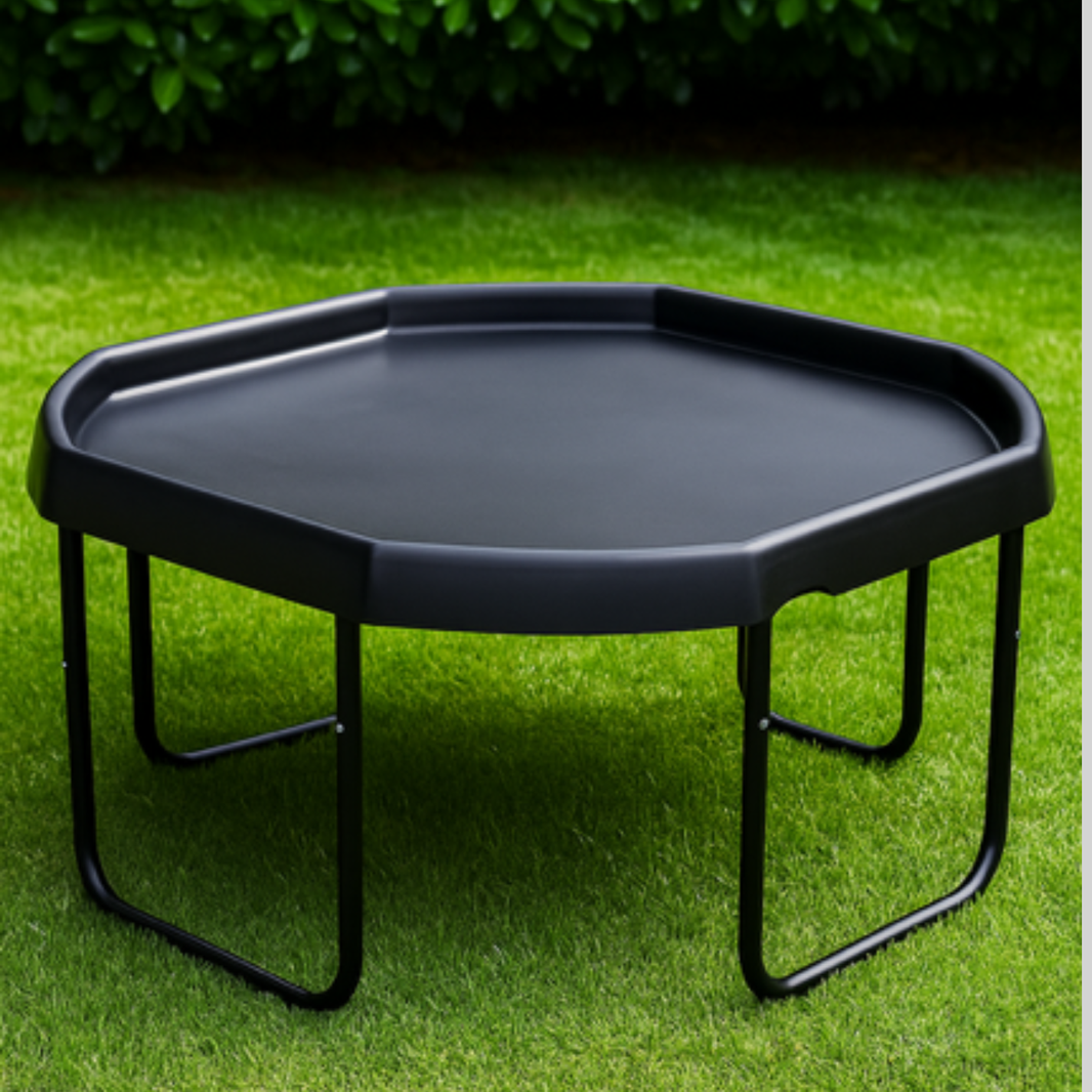 Tuff tray stand with black tuff tray, photographed on green grass with dark foliage in the background.